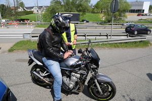 na pierwszym planie znajduje się motocyklista na motorze, za nim policjant, w oddali widać przejście dla pieszych.