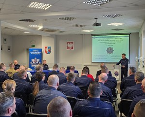 Na zdjęciu widoczna na pierwszym planie publiczność w postaci funkcjonariuszy KPP Chrzanów i jednostek podległych, dalej zaproszeni goście, przy stole po środku Komendant Wojewódzki Policji w Krakowie nadinsp. Artur Bednarek, po lewej p.o. 1-szy Zastępca Komendanta Powiatowego Policji w Chrzanowie podinsp. Rafał Kaczmarczyk, przy pulpicie p.o. Komendant Powiatowy Policji w Chrzanowie podinsp. Zbigniew Zacher.