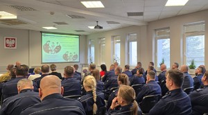 Na zdjęciu widoczna na pierwszym planie publiczność w postaci funkcjonariuszy KPP Chrzanów i jednostek podległych, dalej zaproszeni goście, przy stole po lewej p.o. 1-szy Zastępca Komendanta Powiatowego Policji w Chrzanowie podinsp. Rafał Kaczmarczyk.