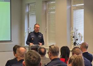 Przy pulpicie stoi Komendant Wojewódzki Policji w Krakowie nadinsp. Artur Bednarek, widoczni poniżej zaproszeni goście i funkcjonariusze Komendy Powiatowej Policji w Chrzanowie.