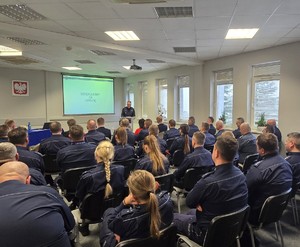 Przy pulpicie stoi Komendant Wojewódzki Policji w Krakowie nadinsp. Artur Bednarek, widoczna jest publiczność, która siedzi na krzesłach, w skład publiczności wchodzą zaproszeni goście oraz Funkcjonariusze Komendy Powiatowej Policji w Chrzanowie i jednostek podległych.