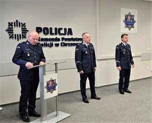 Na zdjęciu od lewej: st. sierż. Grzegorz Martens - pełniący rolę lektora, stoi przy pulpicie, następnie stoi podinsp. Grzegorz Żmudka, obok niego stoi podinsp. Zbigniew Zacher.