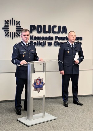Na zdjęciu p.o. Komendant Powiatowy Policji w Chrzanowie podinsp. Zbigniew Zacher stojący przy pulpicie, obok stoi p.o. Pierwszego Zastępcy Komendanta Powiatowego Policji w Chrzanowie podinsp. Grzegorz Żmudka, który trzyma w ręku teczkę z dokumentem.