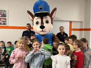 Dzieci stojące przed maskotką, obok maskotki Dzielnicowi KP Libiąż.
