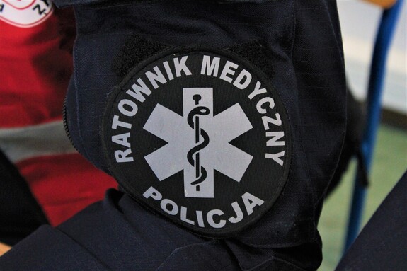Zbliżenie na rękaw munduru z napisem „Ratownik Medyczny Policja” i symbolem medycznym.
