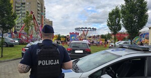 Policjant stojący przy radiowozie, obserwujący Dni Libiąża.