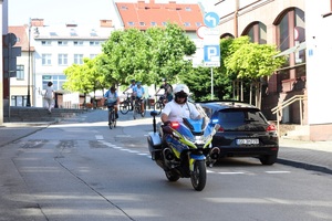 Policjant WRD KPP Chrzanów poruszający się motocyklem służbowym z włączonymi światłami uprzywilejowania, podczas zabezpieczenia rajdu rowerowego.