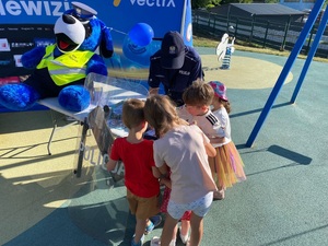 Policjantka podczas rozmowy z dziećmi przy stoisku profilaktycznym.