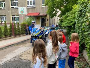 Przedszkolaki stojące na terenie zewnętrznym przedszkola podczas prelekcji Policjantów.