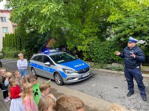 Policjant stojący przed przedszkolakami podczas prelekcji.