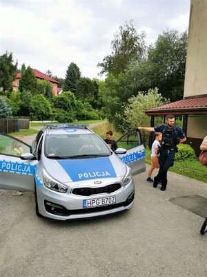 Policyjny radiowóz zaparkowany przed Wiejskim Domem Kultury w Karniowicach podczas spotkania z dziećmi.