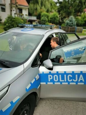 Dziecko ogląda wnętrze oznakowanego radiowozu policyjnego podczas spotkania z dzielnicowymi.