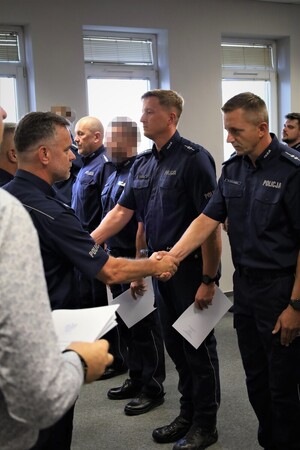 Komendant Powiatowy Policji w Chrzanowie wręcza policjantowi akt mianowania na wyższy stopień służbowy. W uroczystości uczestniczą pozostali funkcjonariusze.
