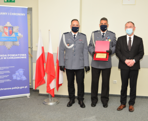 Komendanci KPP w Chrzanowie wraz z Starostą Chrzanowskim. Komendant KPP w Chrzanowie trzyma w rękach tablicę z podziękowaniami od Starosty za trud i odwagę policjantów w codziennej służbie