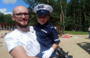 Dziecko przebrane za policjanta Ruchu Drogowego na rękach swojego opiekuna