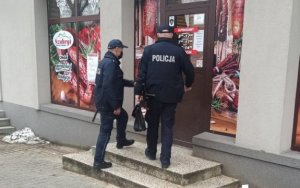 Na zdjęciu dwóch umundurowanych policjantów wchodzi do jednej z placówek handlowych