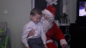 Na zdjęciu funkcjonariusz przebrany za Mikołaja wręcza prezent 5 letniemu chłopcu
