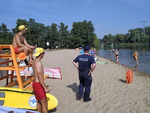 Na zdjęciu widać policjanta Wydziału Prewencji który patroluje plaże, na zdjęciu widoczni są także ratownicy WOPR