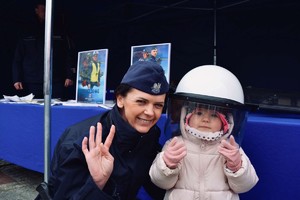 Na zdjęciu umundurowana funkcjonariuszka wraz dzieckiem, który ma ubrany na głowie kask.