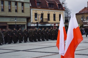 Na zdjęciu widać umundurowanych żołnierzy WOT stojących w dwuszeregu, w tle widać flagę biało – czerwoną